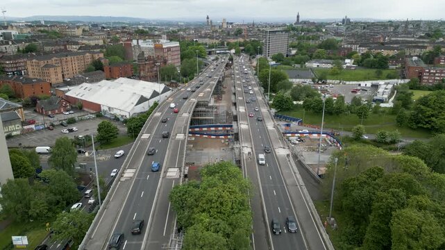 Aerial drone view of traffic on motorway viaducts/bridges, with lanes closed due to ongoing repairs, in Glasgow, Scotland, UK. Glasgow city's skyline is in the background.