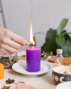 Woman lighting a purple candle

