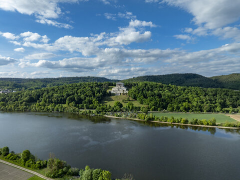 Aerial view of the Walhalla memorial overlooking the Danube river and lush green hills under a blue sky with white clouds in Donaustauf, Bayern, Germany.
