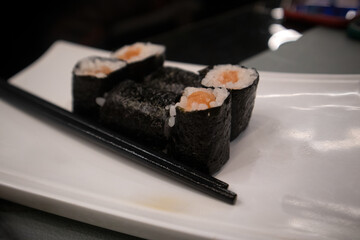 Assortimento di sushi maki giapponesi con salmone e avocado avvolti in alga nori serviti su un piatto bianco © Ilarialapreziosa