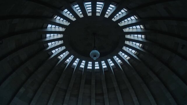 Sunlight passing clerestory windows casting bands across domed ceiling, highlighting pendant globe