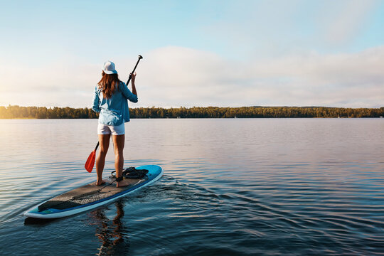 Woman, back view and water with paddle board for outdoor adventure, journey or sightseeing vacation. Nature, female person or paddling with oar on river, lake or space for peaceful trip in wilderness