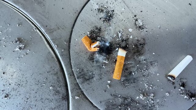 Extinguished Cigarette Butts with Ash and Smoke in Metal Ashtray