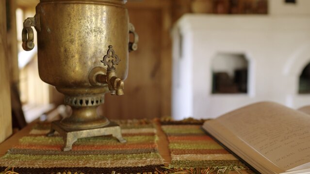 Vintage brass samovar and handwritten book on table in rustic interior
