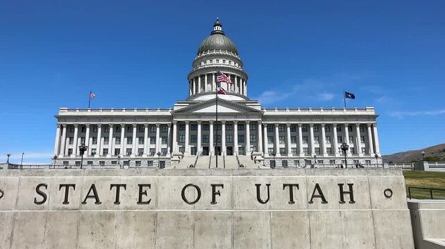 Utah State Capitol Building with flags blowing in the wind against blue sky in Salt Lake City, UT, USA 