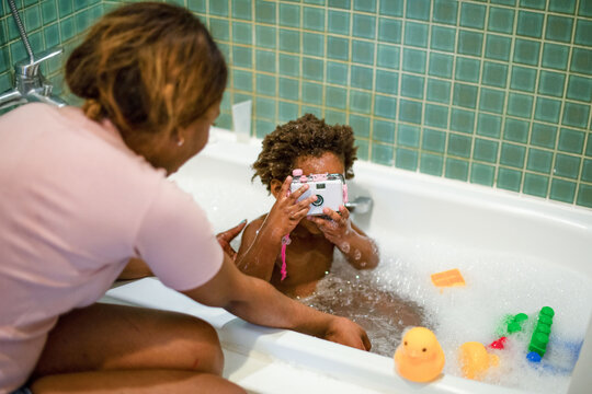 Child photographing in bubble bath.