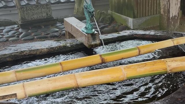 Traditional tsukubai stone fountain stands in a temple yard. This stone basin is located at Raizan Sennyoji Daihioin temple grounds in Fukuoka, Japan. 