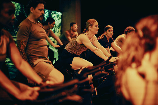 Women and men in a group indoor cycling class pushing through an intense fitness workout together