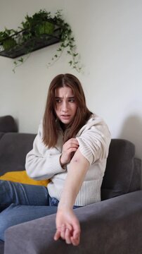 Vertical screen Young woman shocked after discovering tick bite on arm while checking dangerous skin reaction and early symptoms of tick borne infection at home