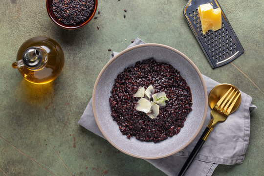 Black rice risotto with cheese and thyme in ceramic plate. Italian Cuisine. Top view