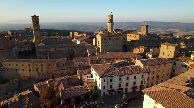 Volterra Sunset Aerial Drone View of Campanile and Baptistery Cathedral Medieval Town on Hilltop Tuscany Italy in Golden Hour Half Orbit Townscape Panorama Scenic Mediterranean Travel Destination