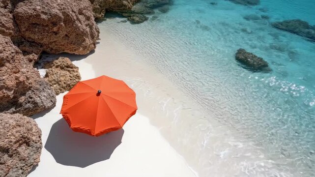 Orange umbrella on pristine white sand beach with turquoise waters and rocky shoreline