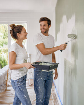 Casal pintando parede durante reforma residencial