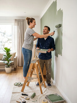 Casal pintando parede durante reforma residencial