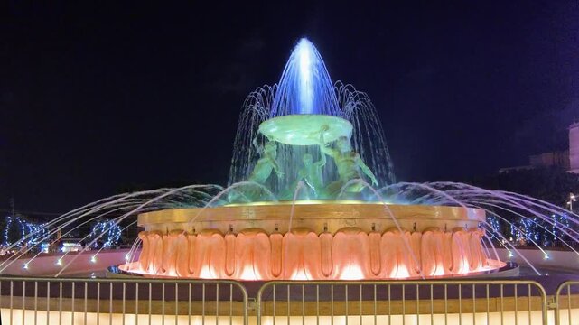 Valletta, Malta, Illuminated Triton Fountain with water feature under a dark evening sky