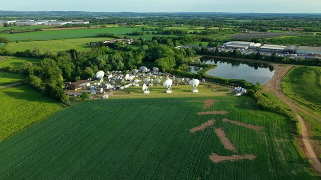 Aerial view of a massive array of satellite dishes and tracking antennas at Rugby Teleport in the rural green landscape of Warwickshire UK