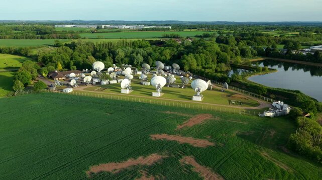 Aerial view of a massive array of satellite dishes and tracking antennas at Rugby Teleport in the rural green landscape of Warwickshire UK