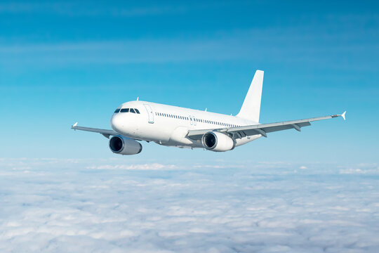 White passenger jetliner flies in the air above the clouds
