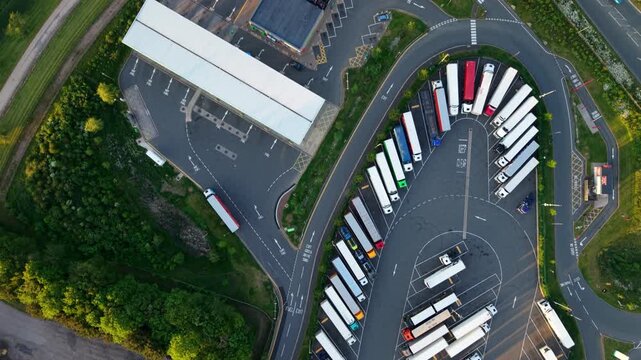 Top Down Aerial Drone Shot of a Large HGV Parking Lot with Rows of Lined Up Trucks and a Fuel Gas Station Forecourt at Rugby Services on the M6 UK