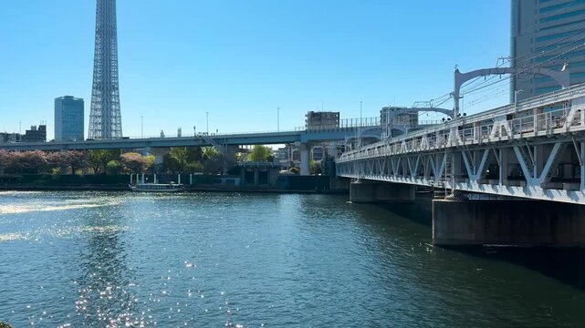 Tokyo Skytree tower and the adjacent Tokyo Solamachi skyscraper rising over the Sumida River in Japan. Industrial metal truss structure of the Tobu Railway Bridge.