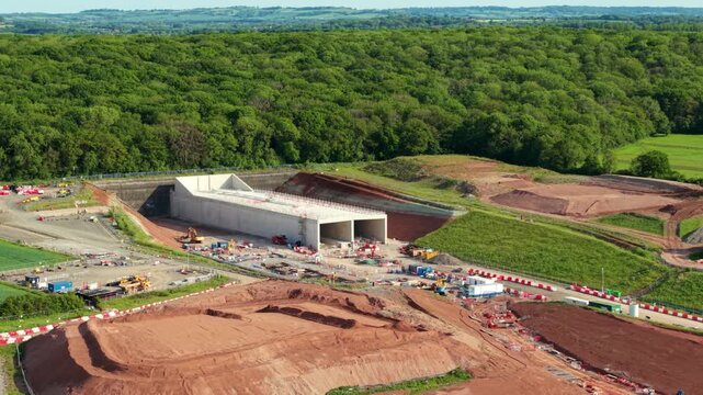 High angle aerial view of a major high speed railway twin bore tunnel entrance surrounded by dense green woodland in Warwickshire