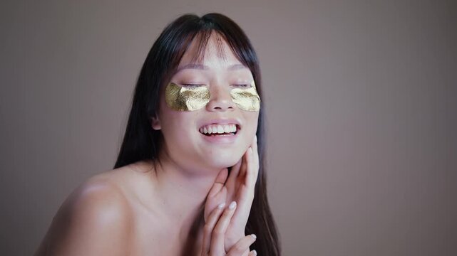 Beautiful asian woman portrait, asian woman applying gold eye patches for skincare