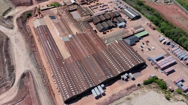 High angle aerial drone view of a massive industrial brick factory and open cast red clay quarry pit for construction manufacturing near Tamworth UK