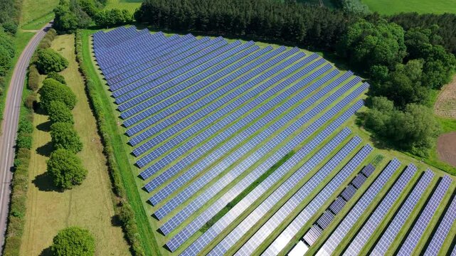 Aerial view of a massive PV solar farm nestled in green rural fields during summer in Tamworth UK