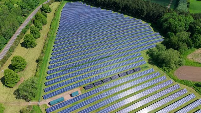 Aerial view of a massive PV solar farm nestled in green rural fields during summer in Tamworth UK