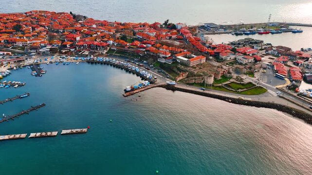 Narrow historic alley with traditional buildings in old town Nesebar. Perspective view of a narrow alley between traditional wooden and stone houses with red tiled roofs in warm sunlight.