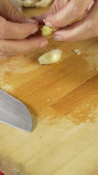 Close up of a woman cutting and crushing garlic with a metal tool