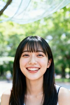 Happy young Japanese woman in her late twenties smiling brightly at the camera in a fresh natural outdoor portrait.
