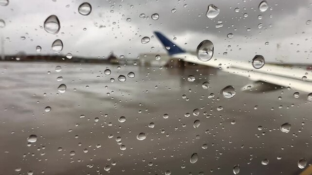 View out of an airplane window on a gray rainy day as the plane is taxiing on the runway. Passenger point of view 