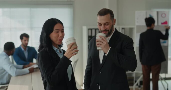 Portrait of Asian and Middle Eastern business colleagues smile and hold coffee cups during break. Coworkers raise drinks together and celebrate progress