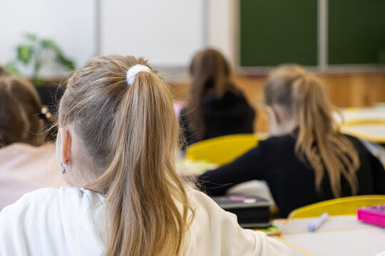 Elementary school children sitting at desks in a classroom, focusing on learning and academic development during a lesson in an educational environment with green chalkboard space