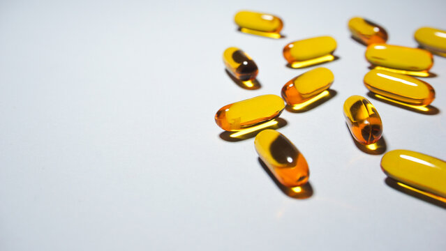 Yellow softgel capsules containing vitamin e. Close up view.