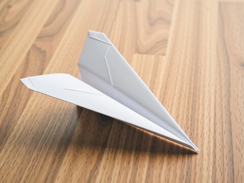 Paper plane resting on wooden desk symbolizing school playground freedom
