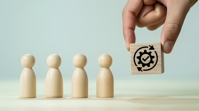 A hand places a gear symbol block near four standing wooden figures on a table