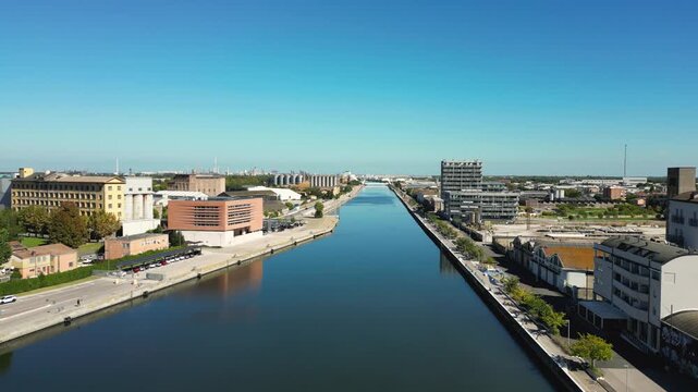 Drone footage of a canal and surrounding cityscape in Ravenna, Emilia-Romagna, Italy, on a clear sunny day.
