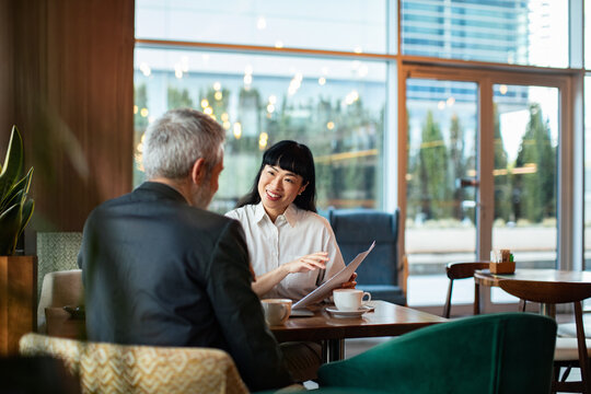 Business professionals discussing documents in modern cafe