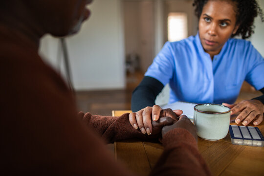 Nurse comforting senior patient during home visit