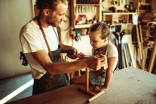 Father teaching daughter woodworking in home workshop