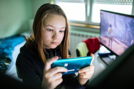 Focused teen girl playing mobile game at home