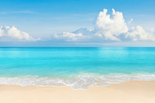 sandy beach of wild island with view of sea waves and white clouds on blue sky