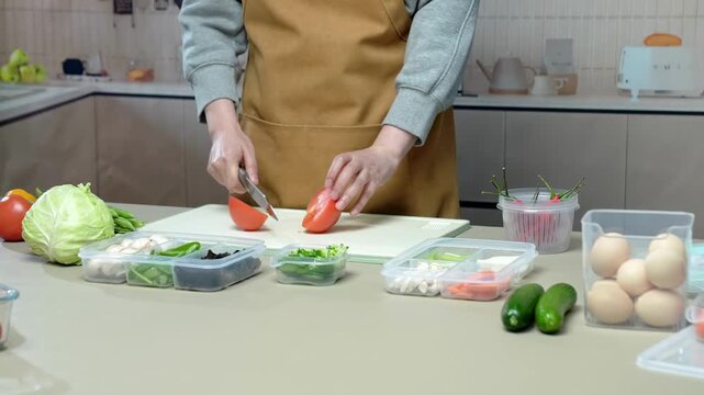 Home cook slicing tomato for fresh vegetable meal prep in kitchen