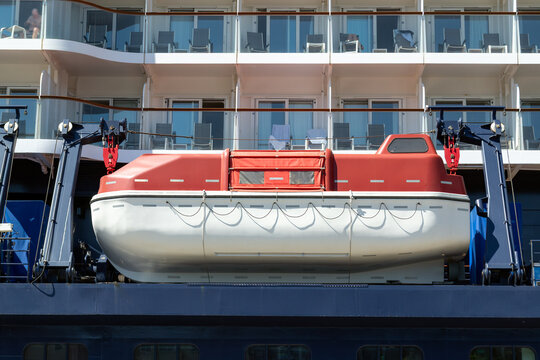 Cruise ship lifeboat on davits against passenger cabins with balconies, maritime safety and luxury travel concept, emergency rescue boat