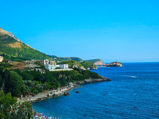 Fototapeta premium landscape sunny day, hills and rocks of Montenegro, city of Budva, white houses visible on the hills. Clear blue sky and bright blue Adriatic sea,