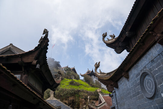Intricate temple roofs with traditional ornaments against a cloudy sky on fansipan mountain