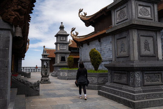 Woman walking among serene temple pagodas and structures at fansipan legend