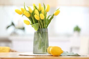 Fototapeta premium Beautiful tulips in vase on wooden table in kitchen
